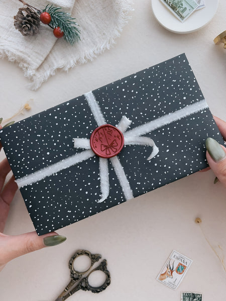 Dark metallic red festive ornament wax seal on a wrapped Christmas gift