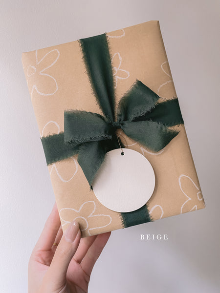 Wrapped gift with Christmas dark green silk ribbon box and Christmas round name tag in beige