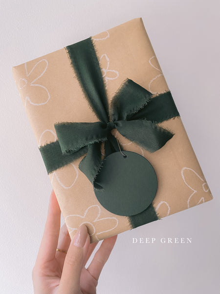 Wrapped gift with Christmas dark green silk ribbon box and Christmas round name tag in deep green