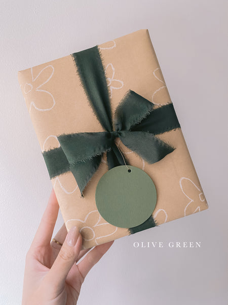 Wrapped gift with Christmas dark green silk ribbon box and Christmas round name tag in olive green