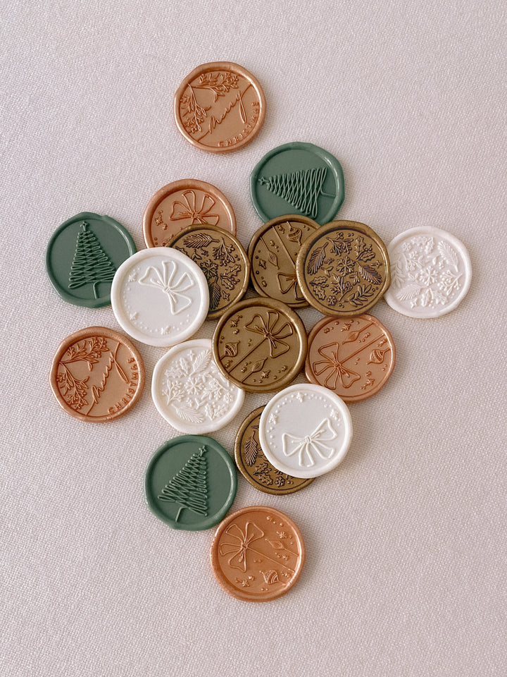 Christmas wax seals in assorted colors and designs in gold, peachy gold, sage green, and antique white