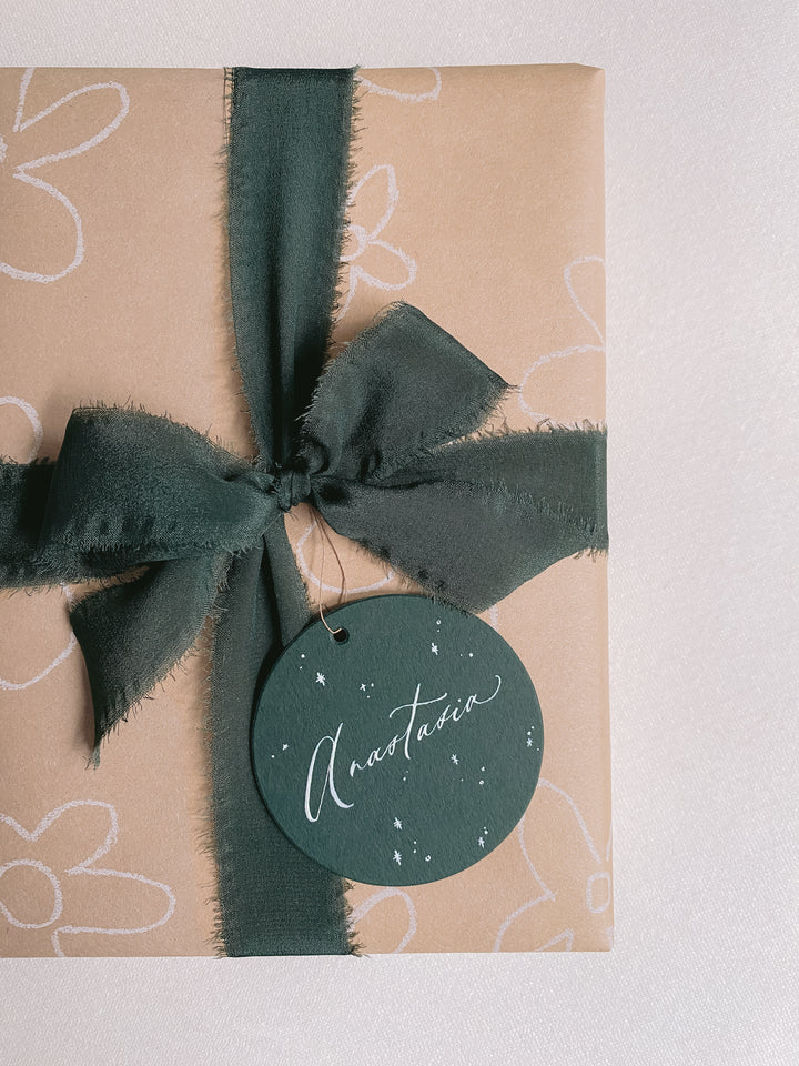 holiday gift wrapped in dark green silk ribbon with a personalized gift tag