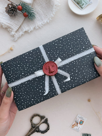 Personalized festive Christmas tree monogram red wax seal on a wrapped Christmas gift