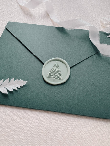 Light pastel green Christmas tree design wax seal on a green Christmas card envelope