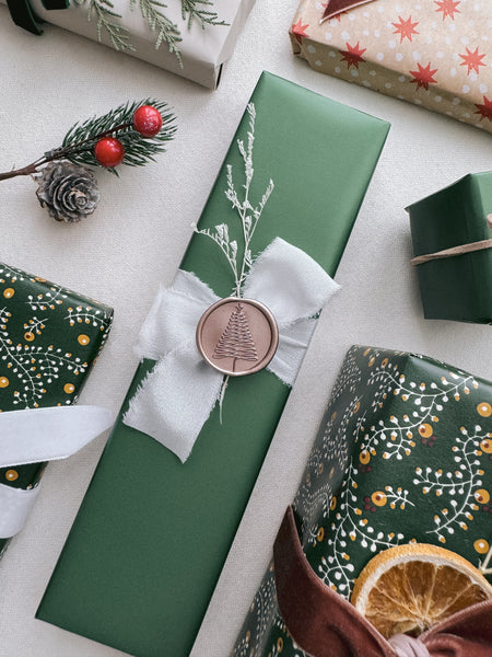 festive gift wrap decorated with torn edge white silk ribbon and a bronze Christmas tree wax seal 