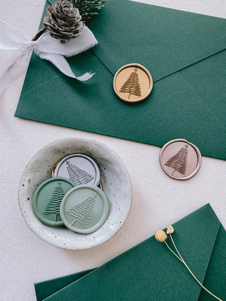 Christmas tree wax seals in silver, green and gold on green Christmas card envelopes