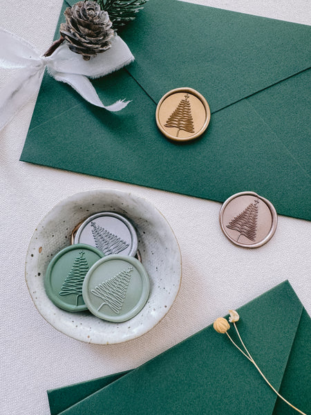Christmas tree design wax seals in gold, green and light bronze, on green Christmas card envelopes