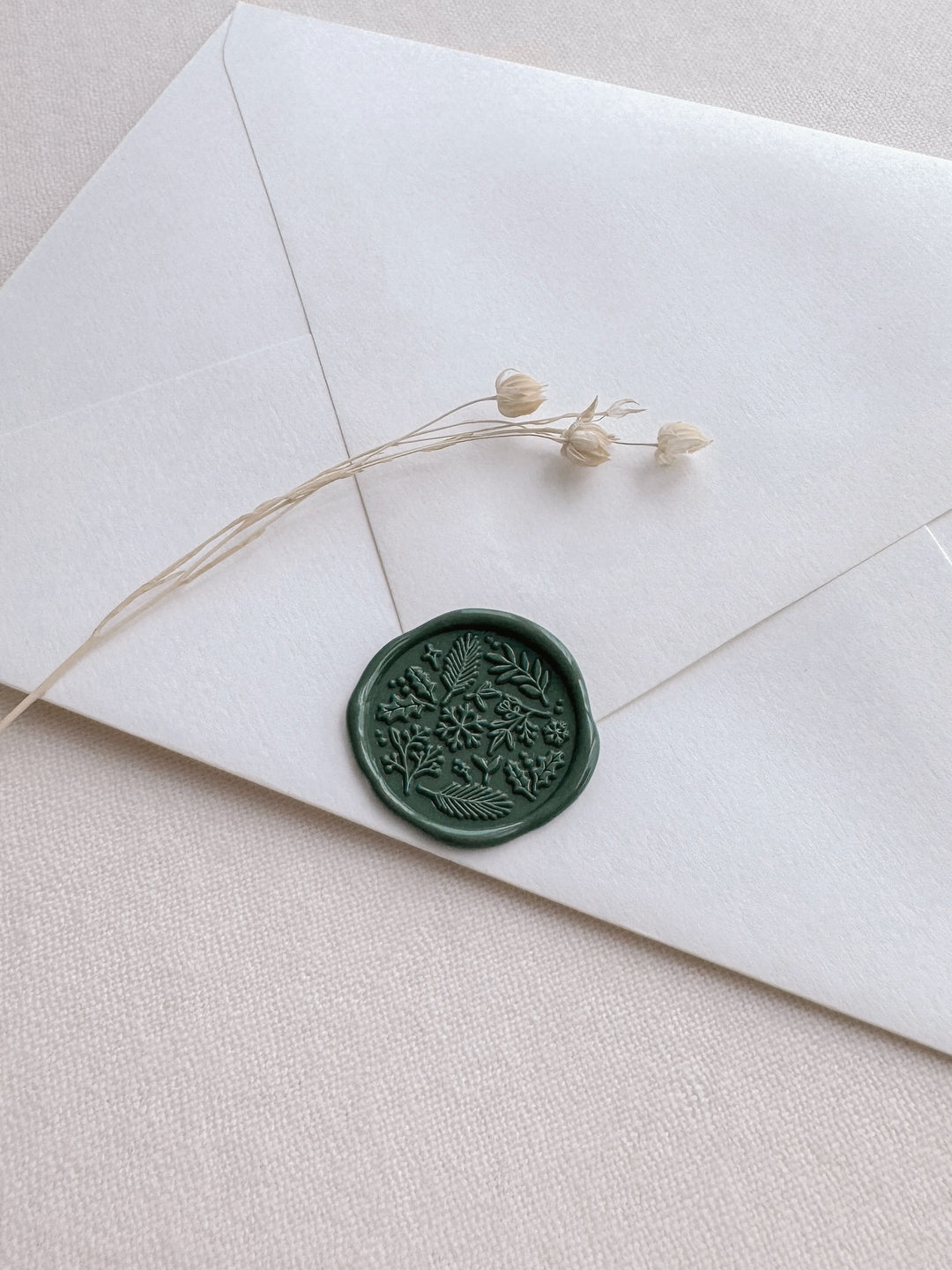 Dark green Christmas wintery botanical design wax seal on a white envelope