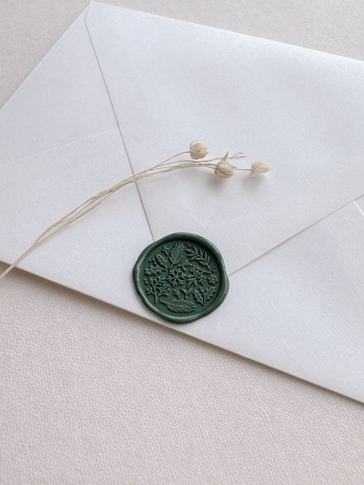 Dark green Christmas wintery botanical design wax seal on a white envelope