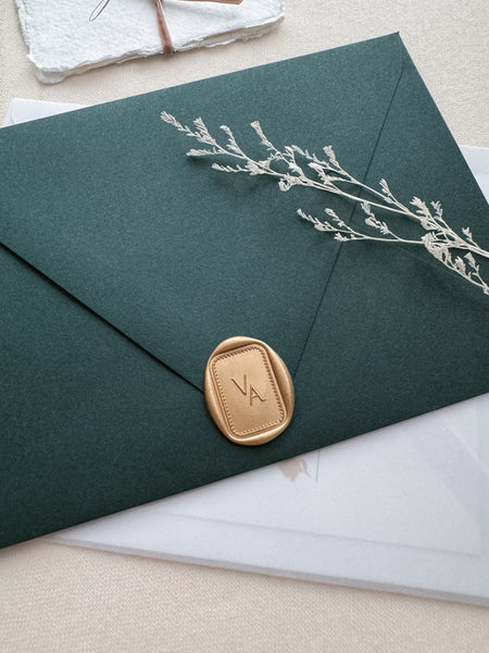 Rectangular border design monogram wax seal in color light gold on a dark green envelope