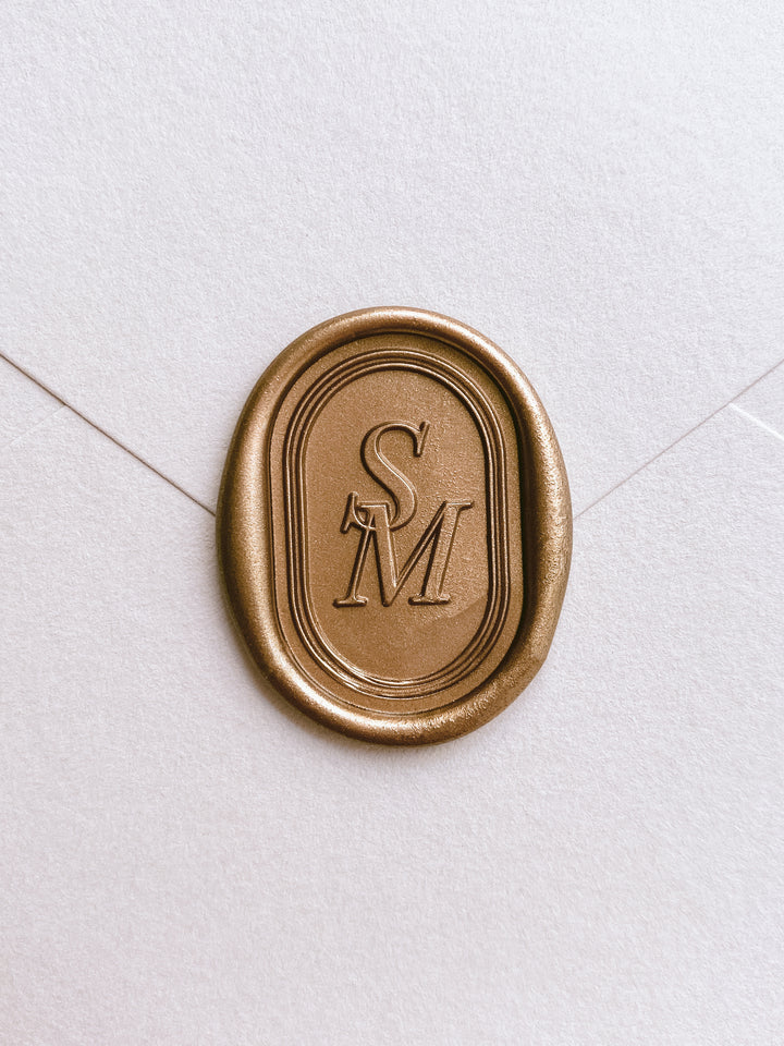 custom monogram oval gold wax seal on a beige envelope 
