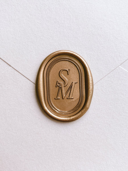 Oval double border design monogram gold wax seal on a off-white envelope