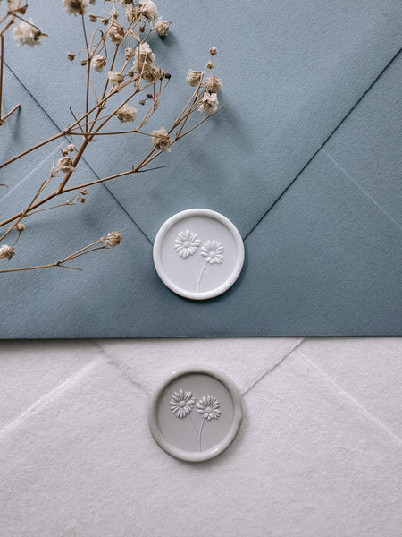 White daisies wax seal on dusty blue envelope and gray daisies wax seal on white handmade paper envelope