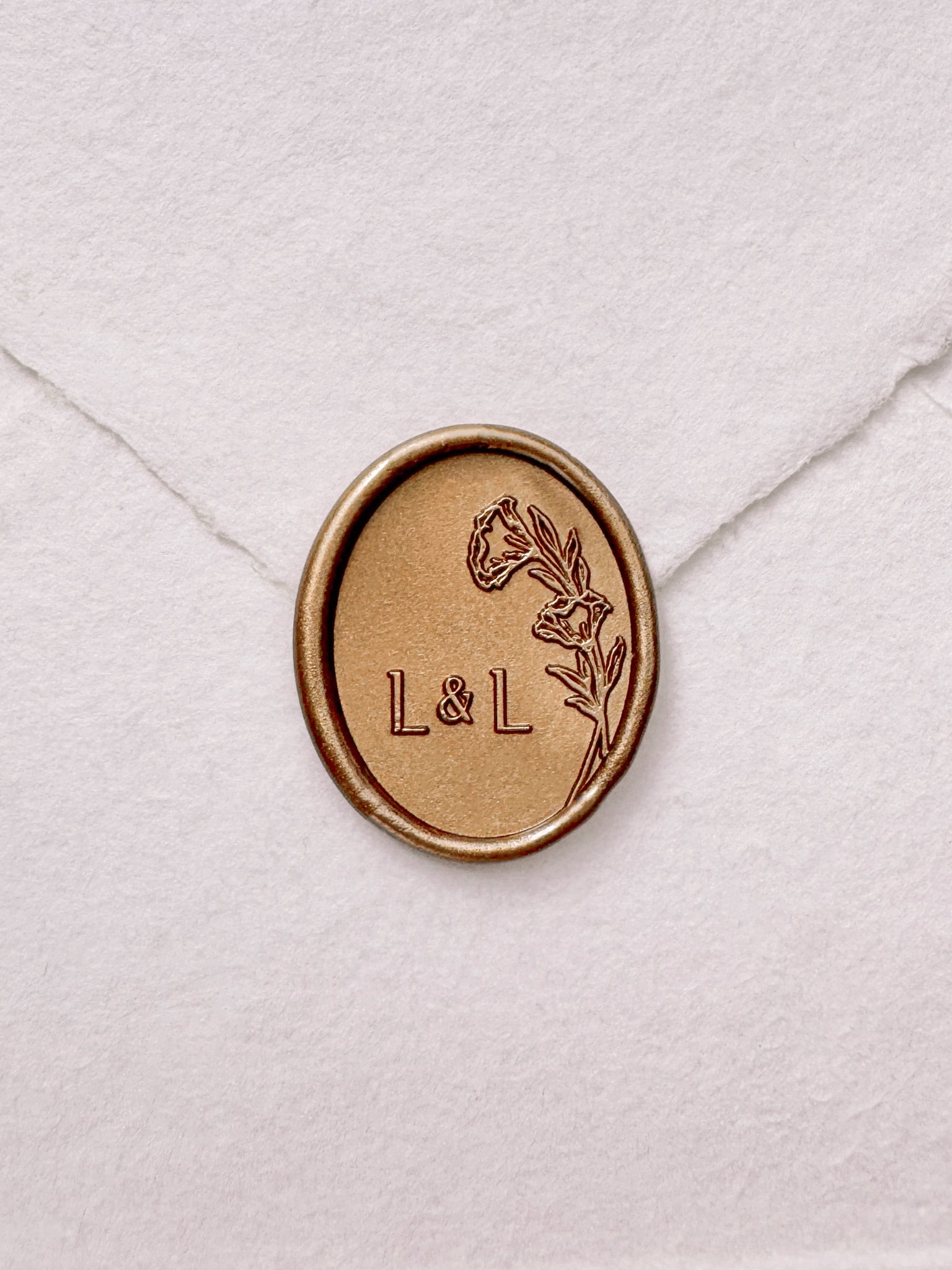 Oval floral monogram gold wax seal on a white handmade envelope