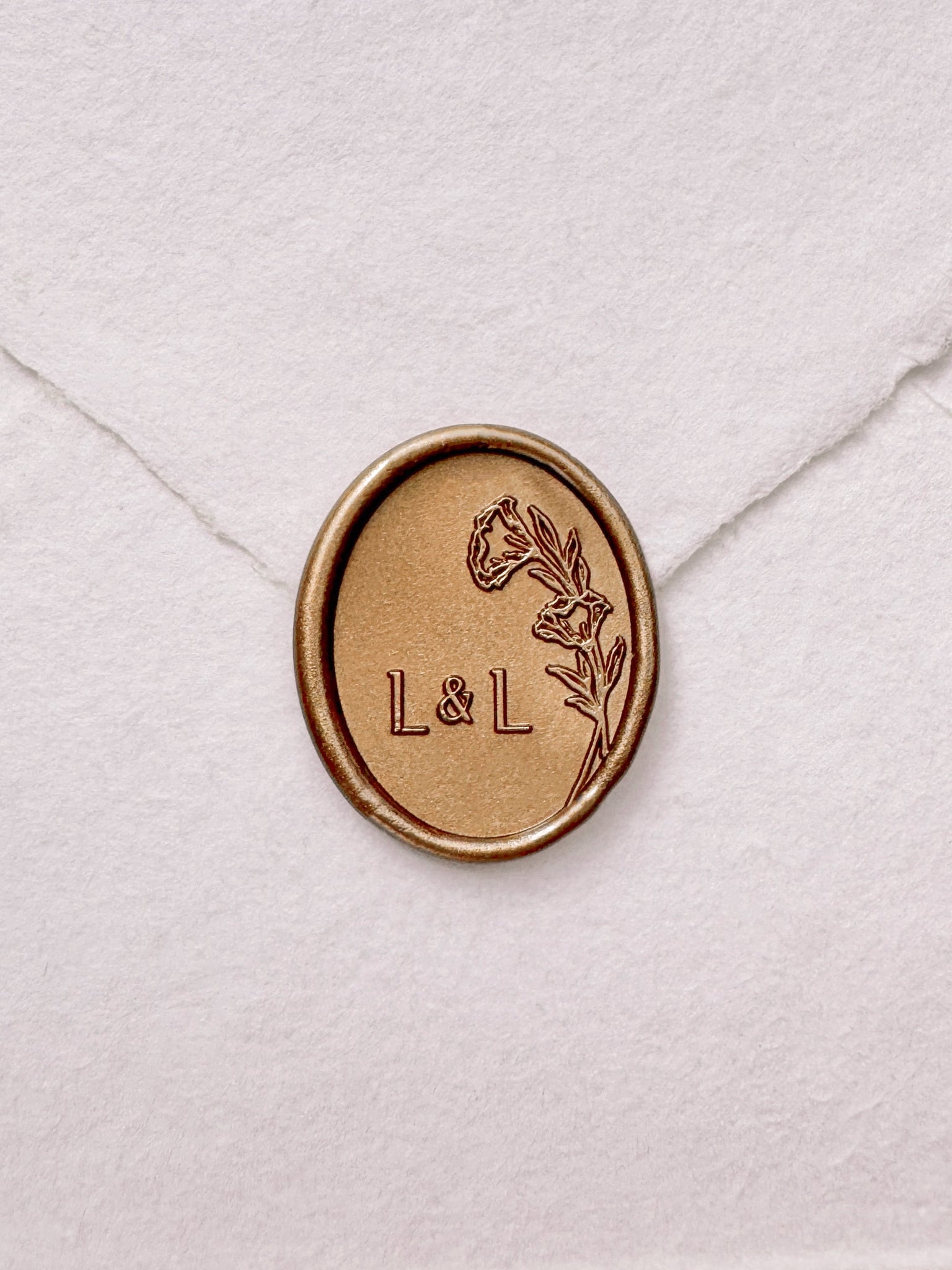 Oval floral monogram gold wax seal on a white handmade envelope