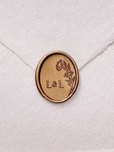 Oval floral monogram gold wax seal on a white handmade envelope