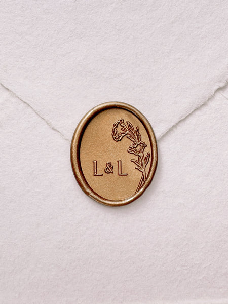 Oval floral monogram gold wax seal on a white handmade envelope