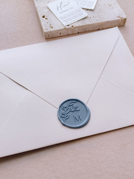 Floral silhouette personalized single initial wax seal in dusty blue on beige envelope