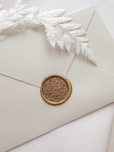 Moroccan tile pattern gold wax seal on beige envelope styled with a white leaf branch