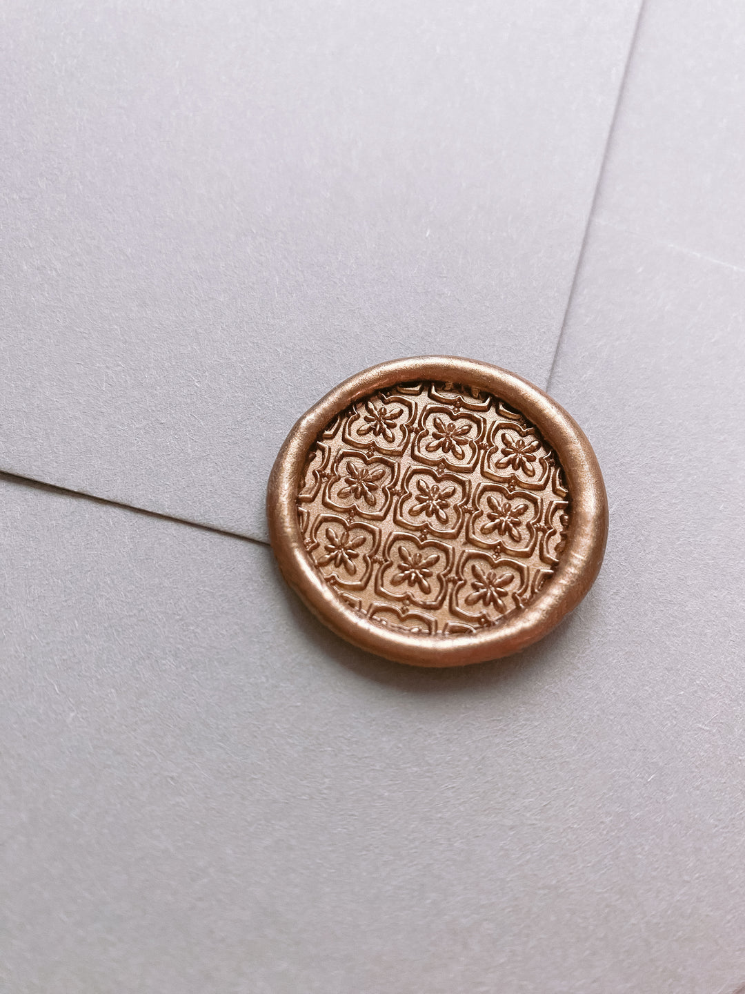 Gold vintage floral pattern wax seal on a light grey envelope 