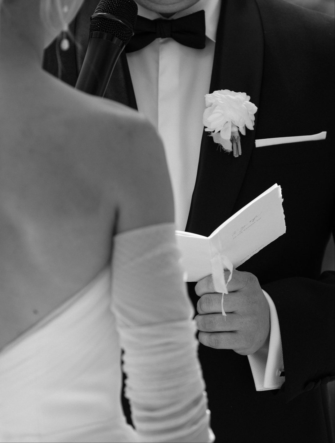 groom holding white vow books at a wedding ceremony