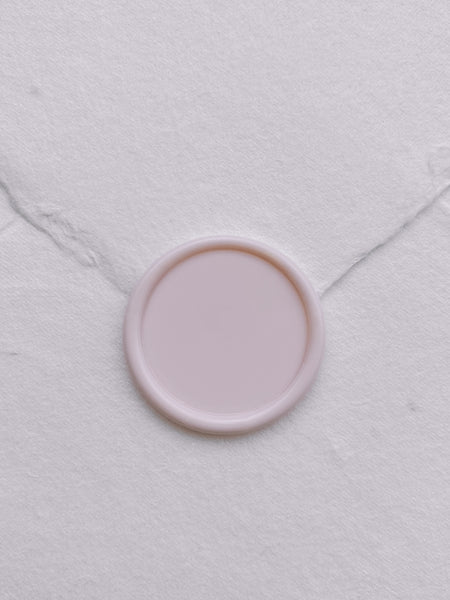 Pale pink blank wax seal on white handmade paper envelope