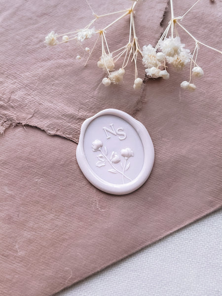 light pink 3D floral monogram wax seal on a pale brown handmade paper envelope 