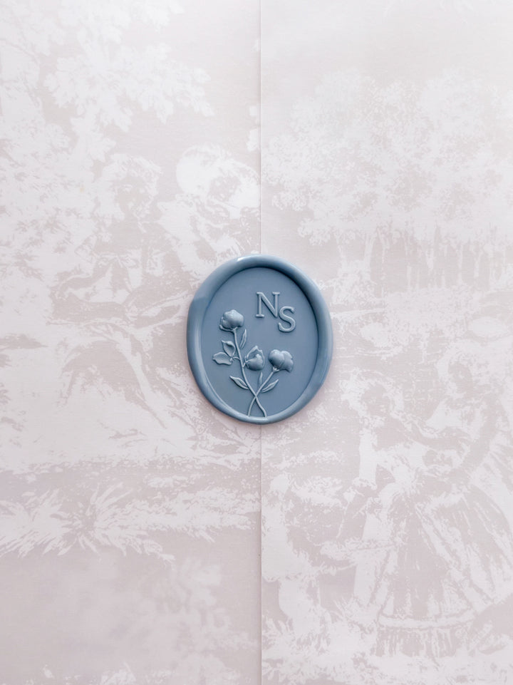 Dusty blue personalized floral monogram oval wax seal on a printed vellum jacket