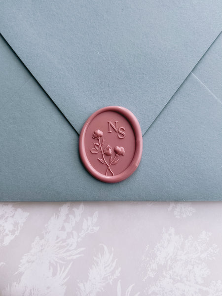 rose colored personalized initials wax seal with 3D floral design on a dusty blue envelope 