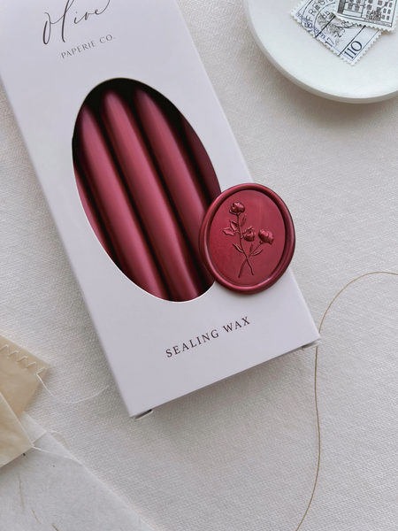 Dark metallic red 3D floral oval wax seal on a box of metallic red sealing wax sticks