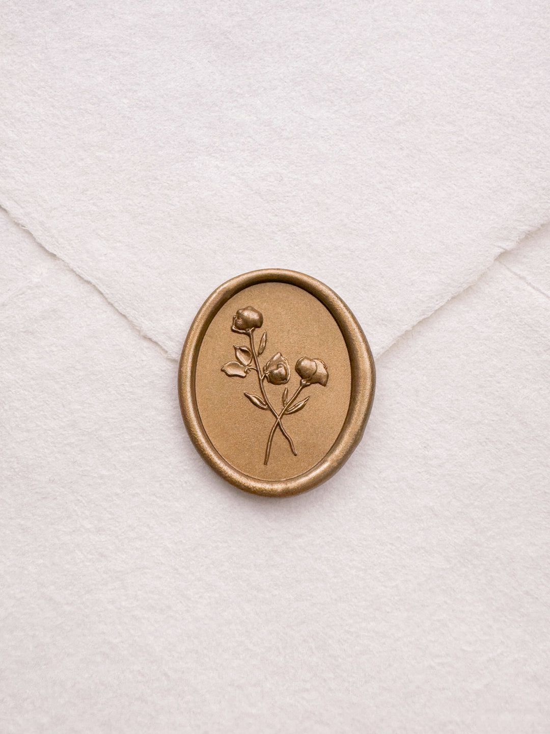 oval 3D floral gold wax seal on a white envelope