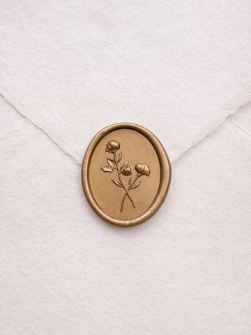 Gold oval floral wax seal on a white handmade paper envelope