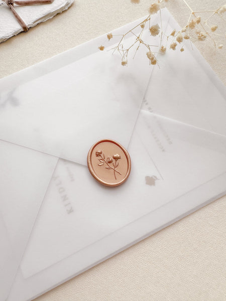 Oval floral wax seal in color peachy gold on a vellum wedding invitation envelope