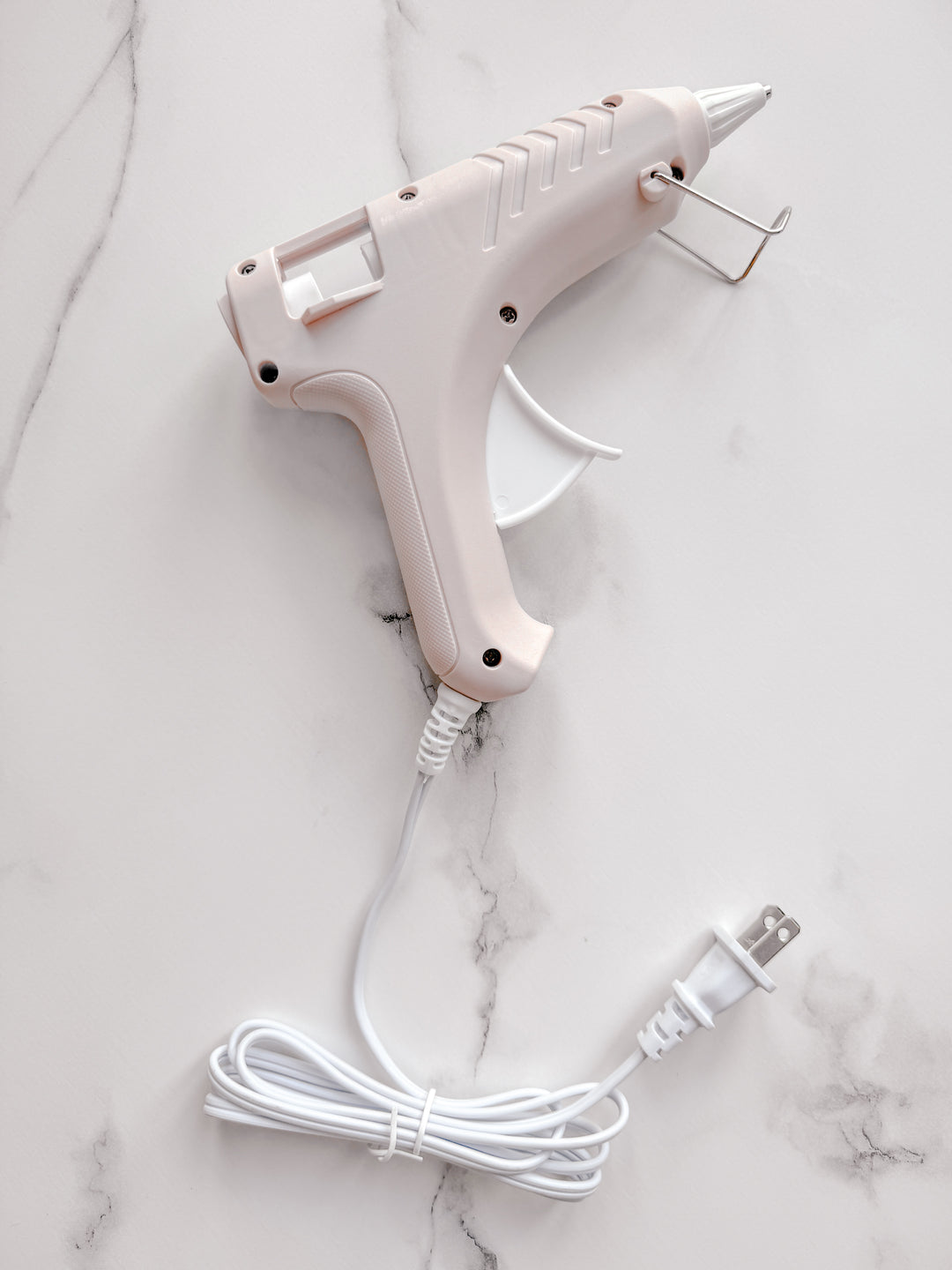 Beige low-temperature glue gun on white marble pattern backdrop