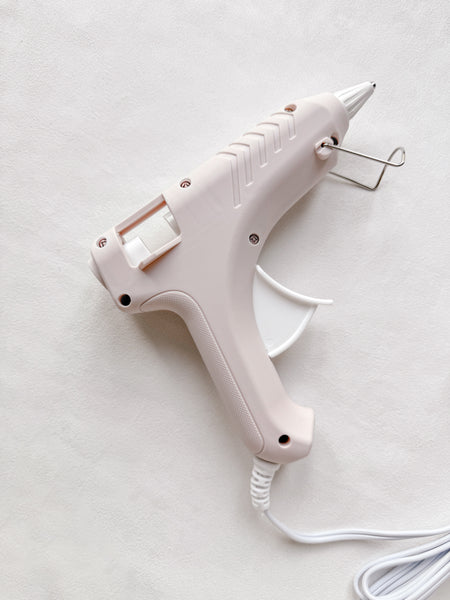 Beige low-temperature glue gun on white backdrop