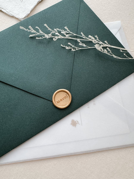 Merci mini wax seal in color light gold on a dark green envelope