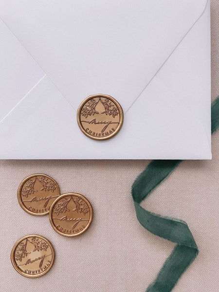 Merry Christmas gold wax seals on a white envelope