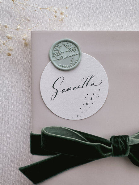 pale green Merry Christmas wax seal on a personalized name tag on a wrapped Christmas gift