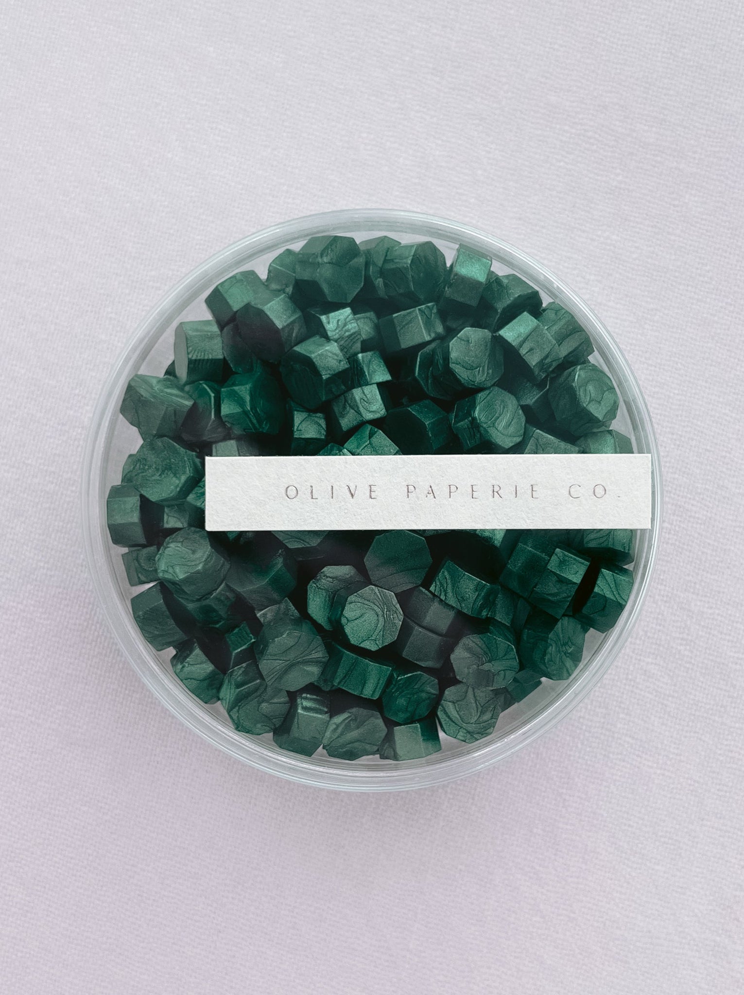 metallic green sealing wax beads in a clear round container