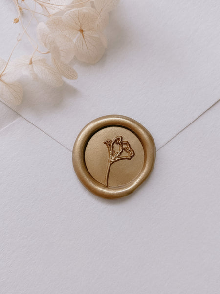 Gold mini flower wax seal on white paper envelope styled with light belge dried hydrangea petals