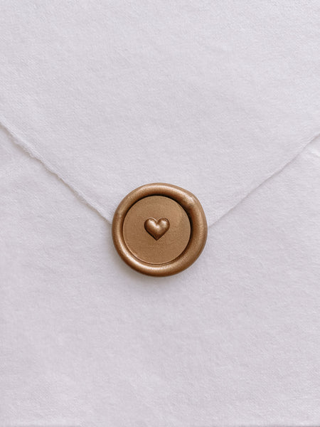 Gold mini heart wax seal on a white handmade paper envelope