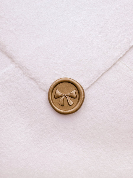 Gold mini 3D engraved ribbon bow wax seal on white handmade paper envelope