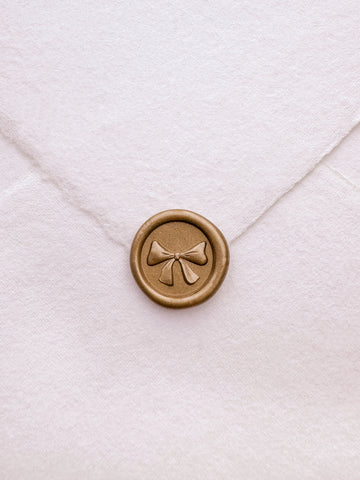 Gold mini 3D engraved ribbon bow wax seal on white handmade paper envelope