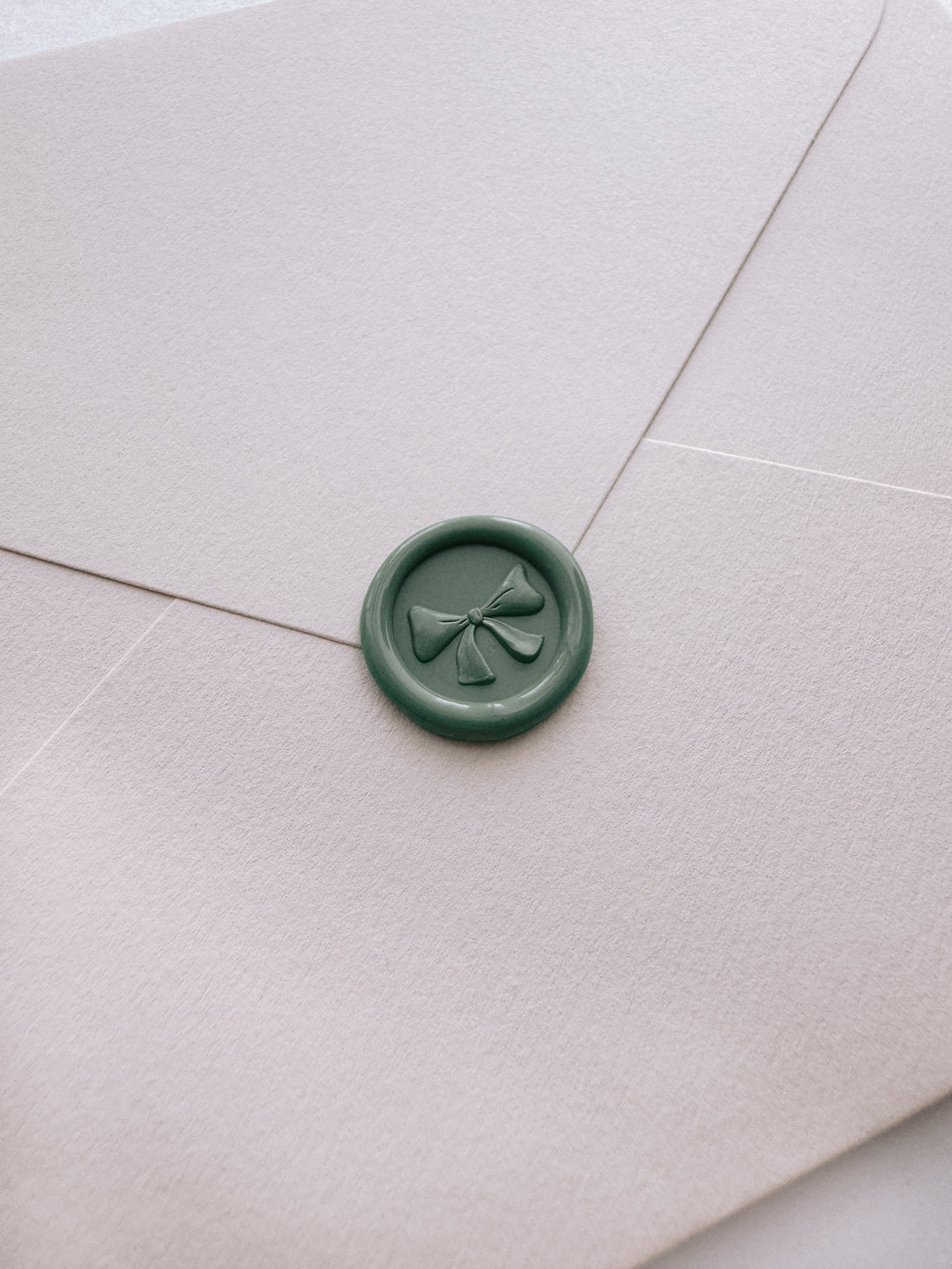 sage green 3D ribbon bow mini wax seal on a light beige envelope