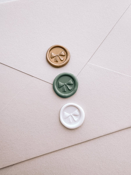 Gold, sage green, and white mini ribbon bow wax seal with 3D engraving on beige envelope