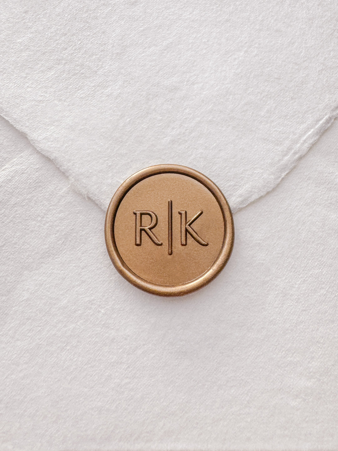 Modern typeface monogram gold wax seal on a white handmade paper envelope