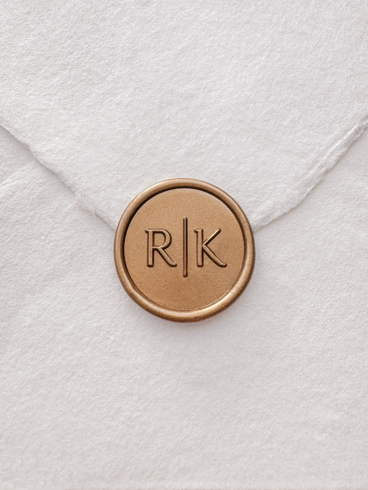 Modern typeface monogram gold wax seal on a white handmade paper envelope