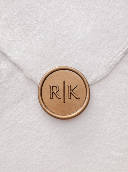 Typeface monogram gold wax seal on a white handmade paper envelope