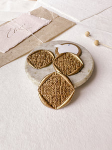Moroccan tile pattern gold square wax seals styled with a small gray stone dish, handmade paper and a dried floral branch