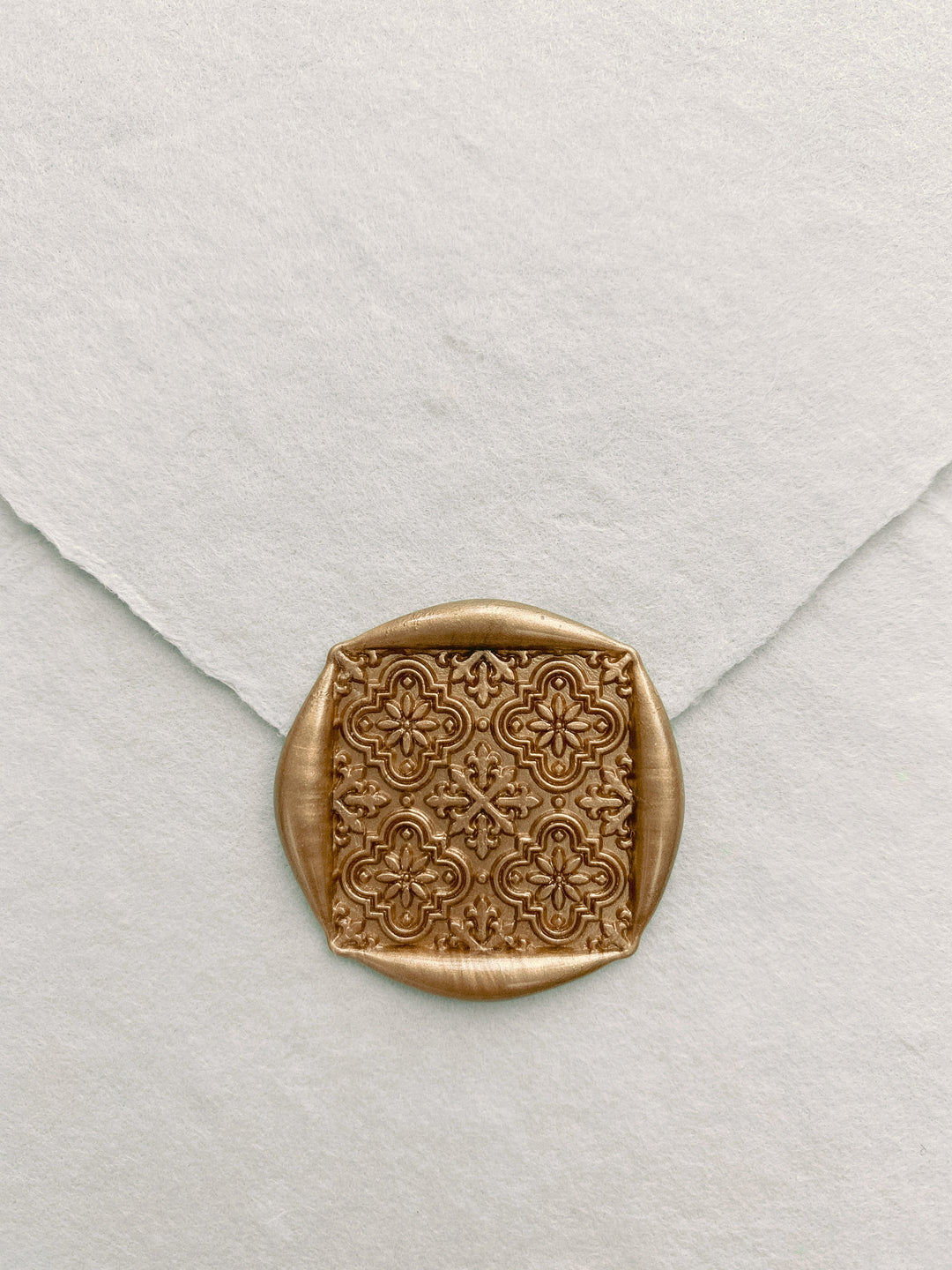 Moroccan tile pattern square shaped wax seal in gold on handmade paper envelope_close up front angle